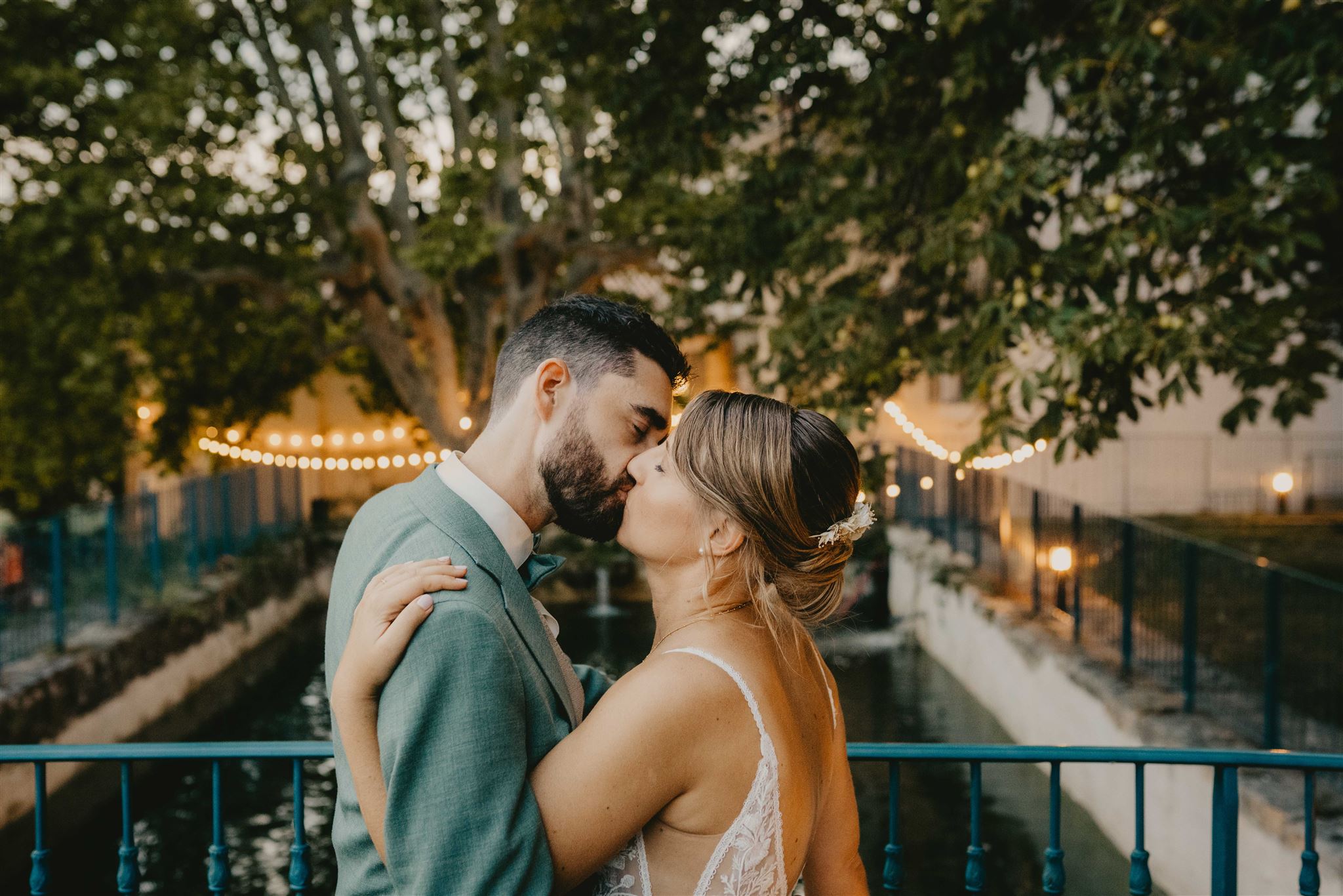 Couple s’embrassant sur le pont du Domaine la Castelette avec l’eau et les guirlandes