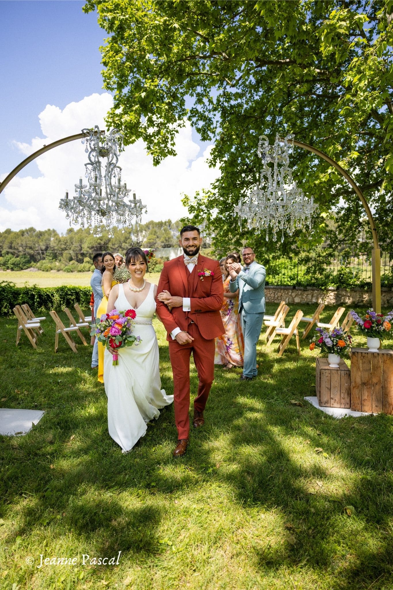 Entrée du couple vers l’arche sous le regard des invités lors d’une cérémonie laïque au Domaine la Castelette